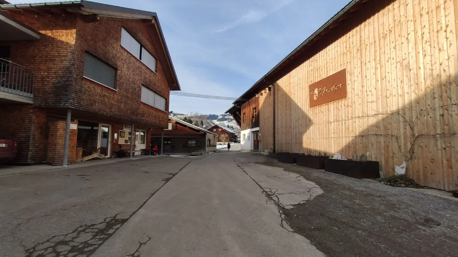 Hofzufahrt mit dem Eingang zum Hofladen links und dem Corten-Schild rechts