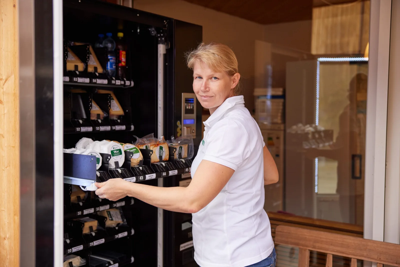 Klaudia Greber füllt Camembert, Münster und Chilikäse in den SB-Automaten am Hof